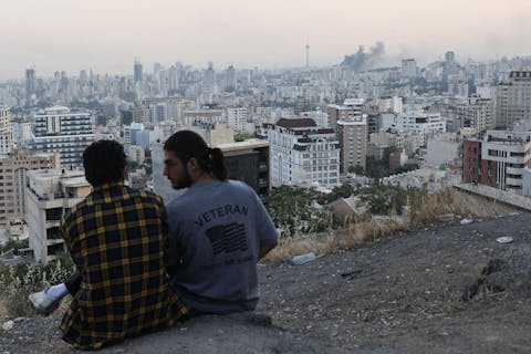 مردی در تهران پس از حمله اسرائیل دود را تماشا میکند.